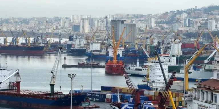 Рукопожатие представителей Омана и Алжира на фоне флагов.