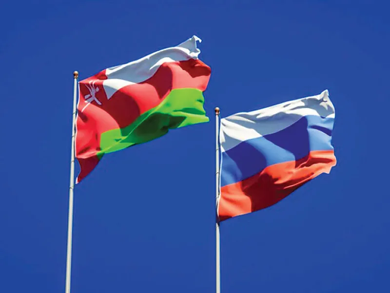Флаги Омана и России на фоне делового центра, символизирующие сотрудничество.